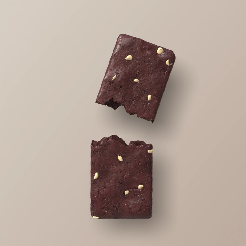 Two dark chocolate bars with gold chips on a beige background